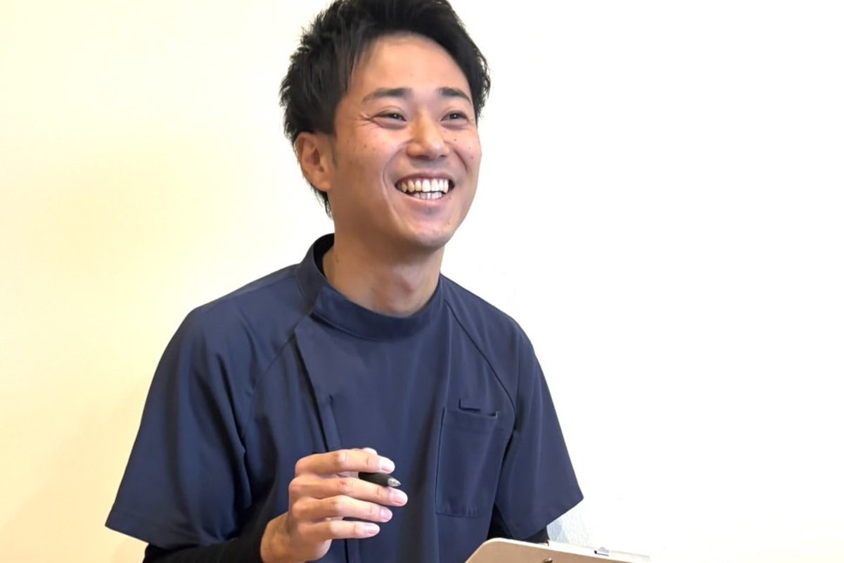 ペンを手に、笑顔で話を聞きながら記録をとる安井先生