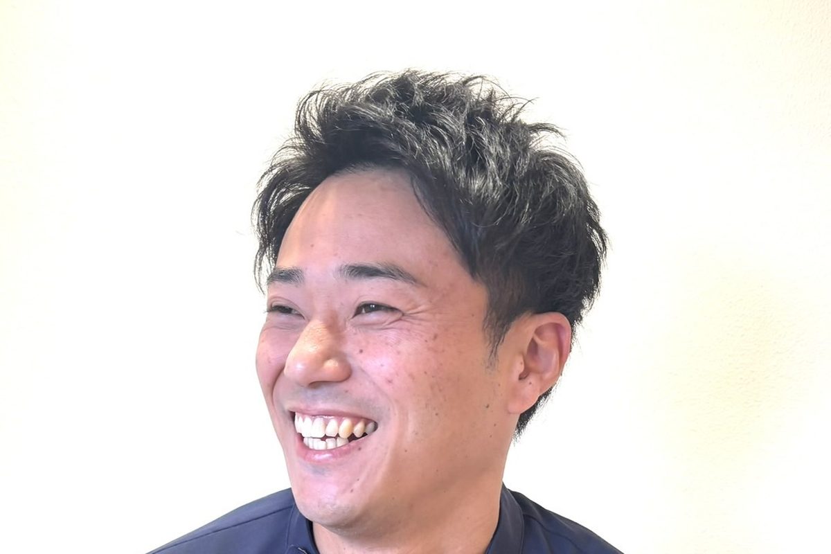 白い壁の前で、声を出して笑う安井先生